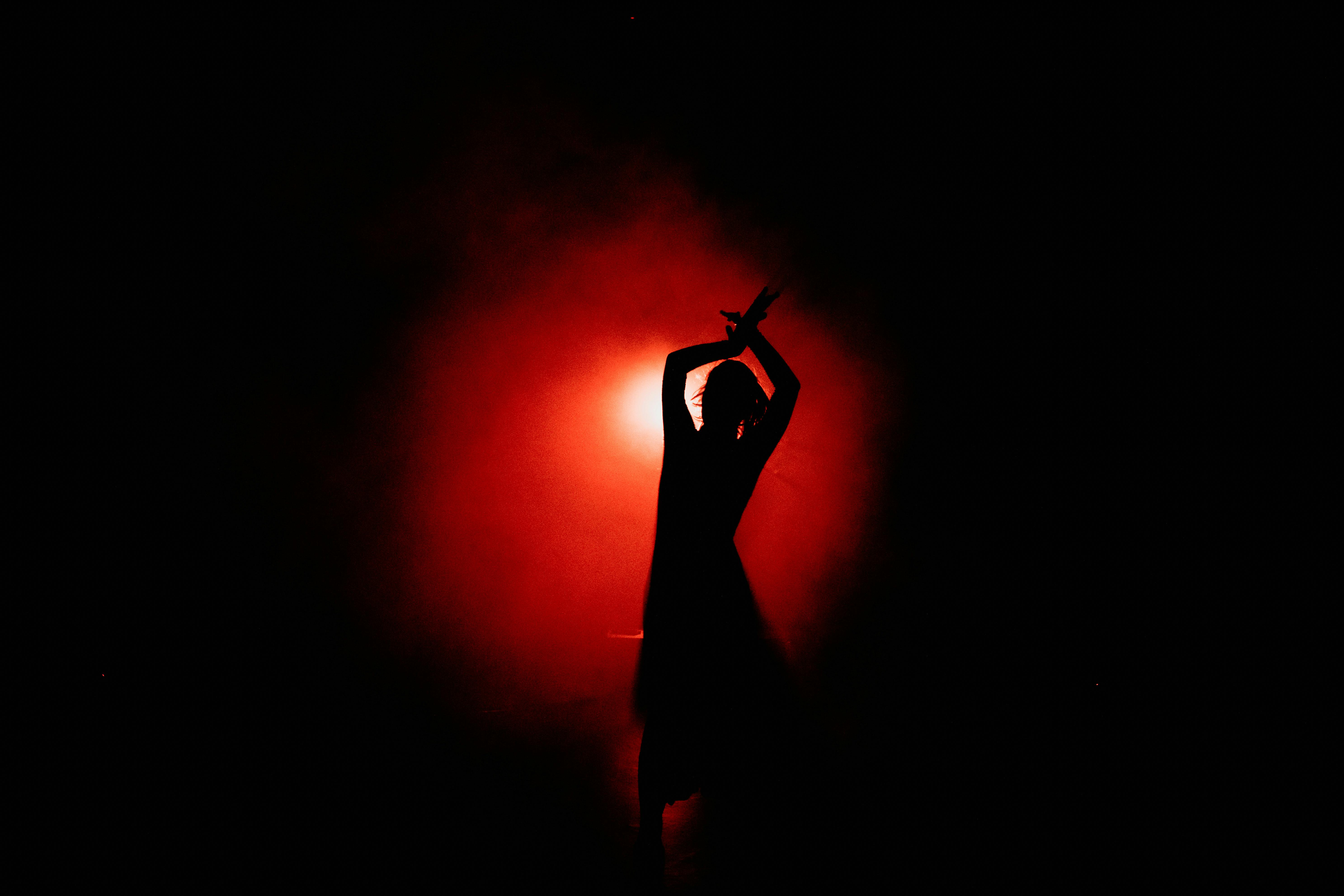 Captivating silhouette of a dancer performing gracefully with a dramatic red background.